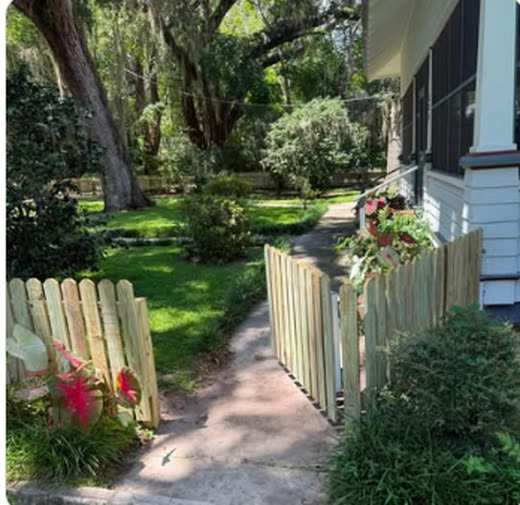 Pressure-treated wood picket fence and walk gate at a landscaped home entry