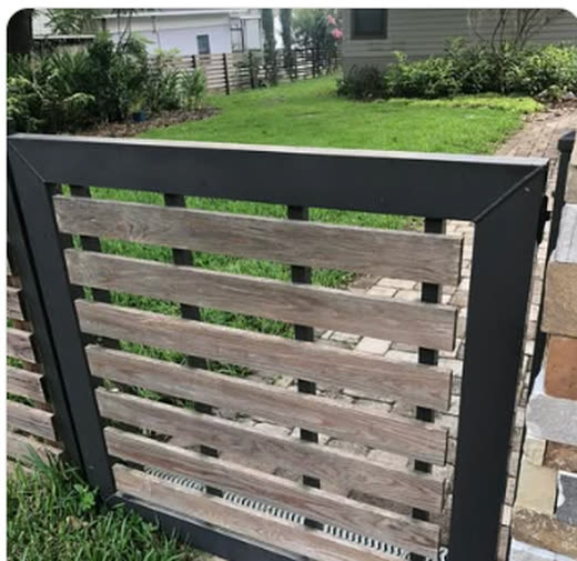 Horizontal wood slat panel set in a powder-coated steel frame beside a stone wall