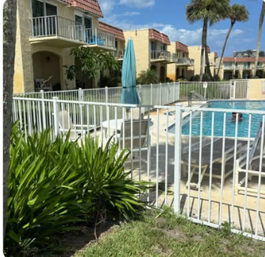White metal pool barrier fence enclosing a condominium pool deck