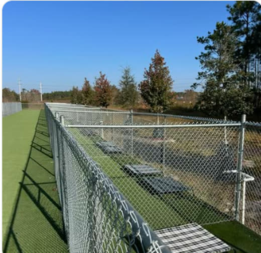 Galvanized chain link fence running the length of a synthetic turf field