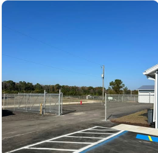 Commercial chain link fence and gate enclosing a newly paved and striped lot
